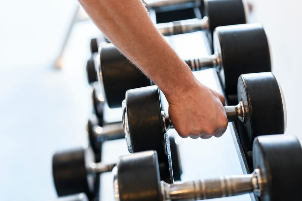 Close detail of a hand selecting a dumbbell